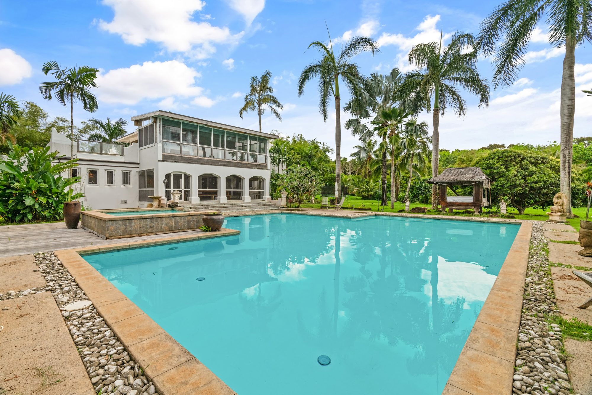 The residence at Banyan Estate seen across the pool, framed by coconut palms